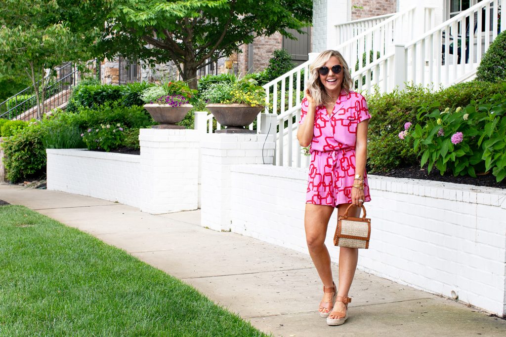 Gibson x Hi Sugarplum Summer of Color Collection by top us fashion blog, Hello Happiness: image of a smiling woman standing outside and wearing the Cavallo Notch Collar Button Down in Pink Chain, geometric cuff bracelets, Menorca Paper Bag Short in Pink Chain, Audrina sandals, Cosmo sunglasses, and holding a Deona crossbody bag. 