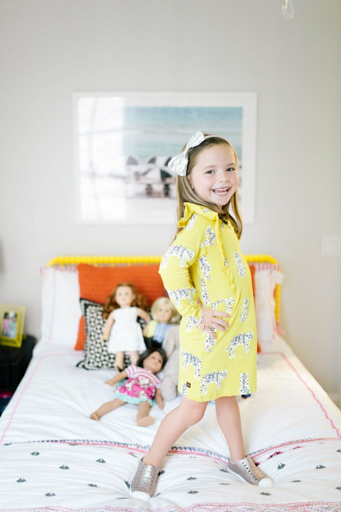 Fashionistas in Training + Nordstrom Kids Clothing by popular Nashville life and style blog, Hello Happiness: image of standing on top of her bed and wearing a Nordstrom Tea Collection Ruffle Dress and Nordstrom Native Shoes Jefferson Bling Glitter Slip-On Vegan Sneaker.