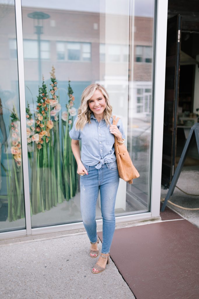 ABLE featured by top US fashion blog Hello! Happiness; Image of a woman wearing a button-up shirt, skinny jeans, earrings and purse from ABLE