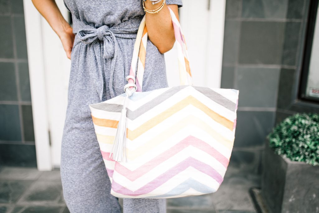 Pretty Pink Lily Favorites...by popular Nashville fashion blog, Hello Happiness: image of a woman wearing a Pink Lily grey Find the Time Jumpsuit, Gills Sneakers, Willa Ford white square earrings, and holding a Striped Jaunt Tote.  