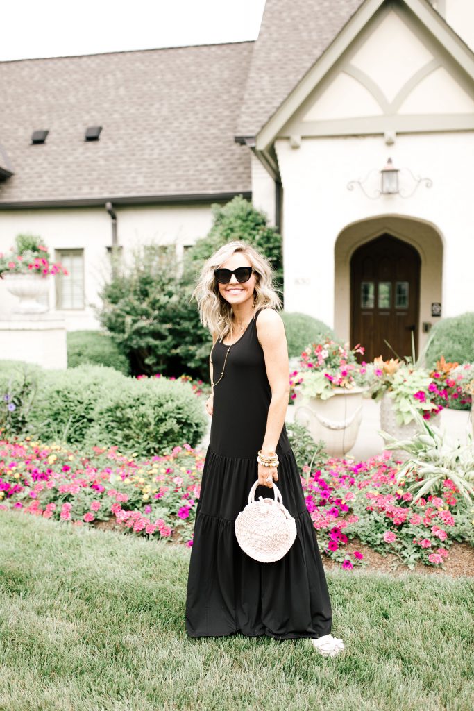 Walmart July Fashion... The Best Black Maxi Dress for Under $50, by popular Nashville fashion blog, Hello Happiness: image of a woman standing outside in front of a white stucco house with pink flower garden beds.  Woman is wearing a black Walmart Women's Hazel Maxi Dress, Women's Circus by Sam Edelman Nicola Bow Slide Sandals, Le Specs sunglasses, and holding a Eliza May Rose Compass Bag.    