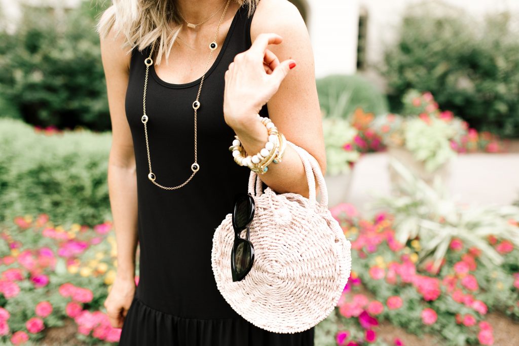 Walmart July Fashion... The Best Black Maxi Dress for Under $50, by popular Nashville fashion blog, Hello Happiness: image of a woman standing outside in front of a white stucco house with pink flower garden beds.  Woman is wearing a black Walmart Women's Hazel Maxi Dress, Women's Circus by Sam Edelman Nicola Bow Slide Sandals, Le Specs sunglasses, and holding a Eliza May Rose Compass Bag.    