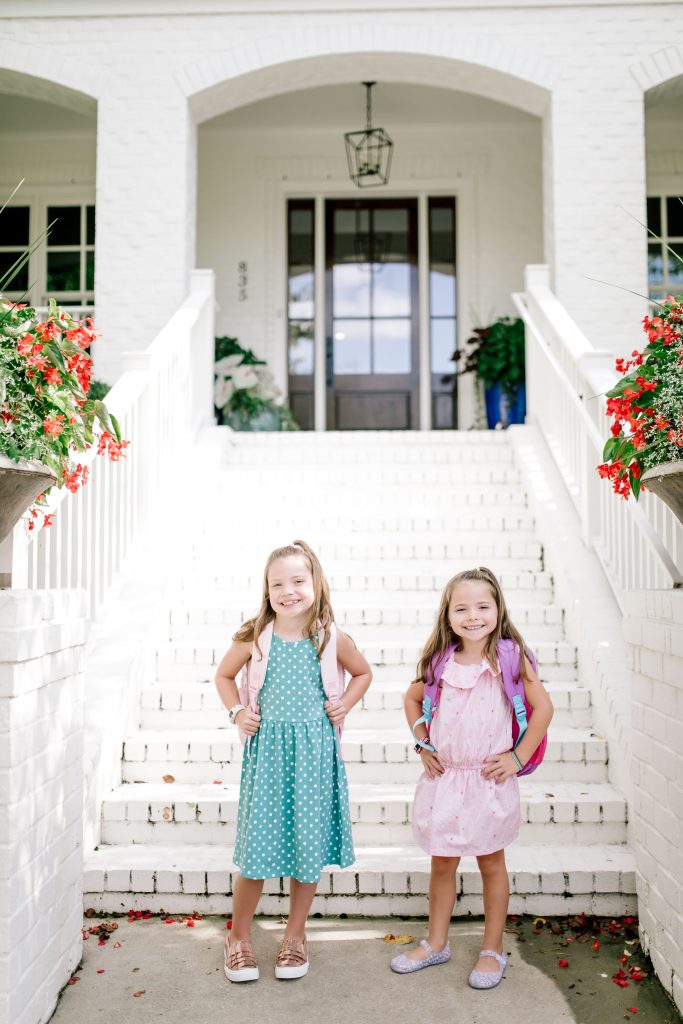 Trend Setting Back-to-School Outfits from Walmart by popular Nashville fashion blog, Hello Happiness: image of two girls standing outside their house wearing a Walmart Dex Girl's Printed A-Line Dress, Wonder Nation Casual Ruffle Chambray Dress, Wonder Nation Girls' Casual Ruffle Slip On Sneaker, and Wonder Nation Children's Casual Jelly Shoe.