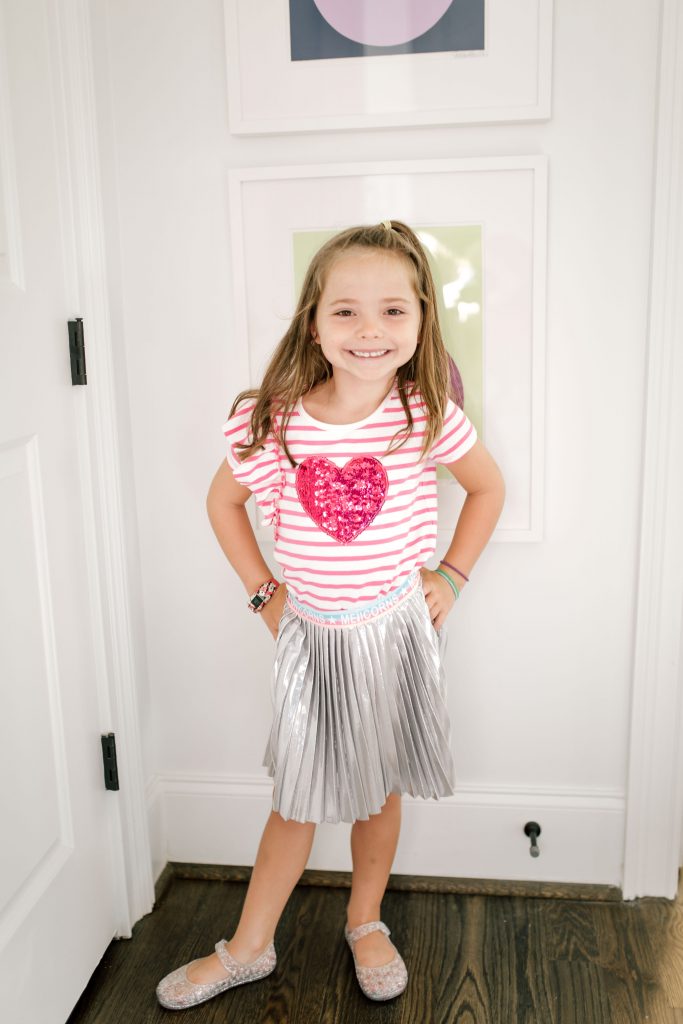Trend Setting Back-to-School Outfits from Walmart by popular Nashville fashion blog, Hello Happiness: image of a girl wearing Walmart 365 Kids From Garanimals Shimmer Foil Pleated Skirt and 365 Kids From Garanimals Flutter Graphic Tank Top. 
