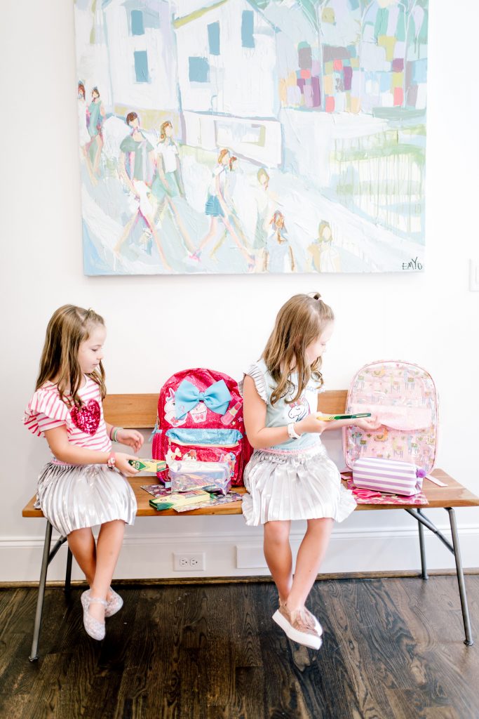 Trend Setting Back-to-School Outfits from Walmart by popular Nashville fashion blog, Hello Happiness: image of two girls sitting on a bench and putting school supplies in their Walmart Wonder Nation Clear Kids Backpack and Jo Jo Siwa Be You! Backpack.
