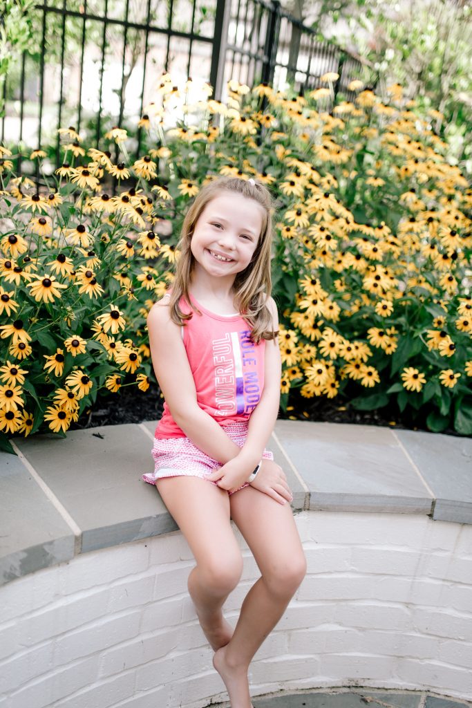 Trend Setting Back-to-School Outfits from Walmart by popular Nashville fashion blog, Hello Happiness: image of a girl sitting outside next to some black eyed Susan flowers and wearing Walmart Athletic Works Graphic Active Tank Racer Back and Athletic Works Active Running Shorts.