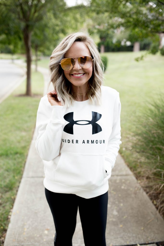 Working on my Fitness...Under Armour Fashion Style by popular Nashville fashion blog, Hello Happiness: image of a woman outside wearing Under Armour HeatGear® Armour Mesh Graphic Ankle Crop, Under Armour® Mid Crossback, Under Armour UA Favorite Fleece Sportstyle Graphic Crew, and Under Armour UA HOVR™ Infinite Mojave women's running shoes.