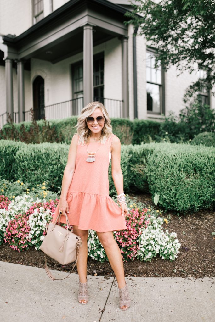The Perfect Game Day Outfit...All the Orange for VOL Football by popular Nashville blog, Hello Happiness: image of a woman standing outside in front of a grey building and wearing a Free People Easy Street Pullover Mini Dress, AERIE CHILL SCOOP LONGLINE BRALETTE, Nordstrom Vince Camuto Kimora Cutout Shield Sandal, shopbop Le Specs Illumination Sunglasses, Prada Daino Tote w/ Top Zip, and David Aubrey jewelry. 