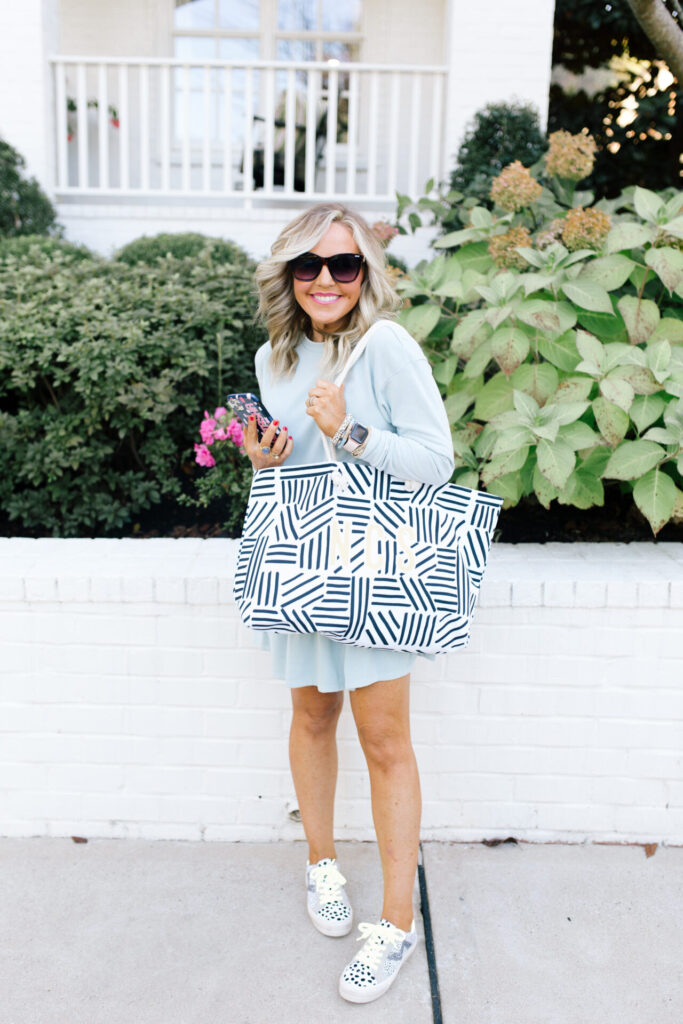 Clairebella Studio by popular Nashville life and style blog, Hello Happiness: image of Natasha Stoneking standing outside and holding a Clairebella X Hello Happiness travel tote. 