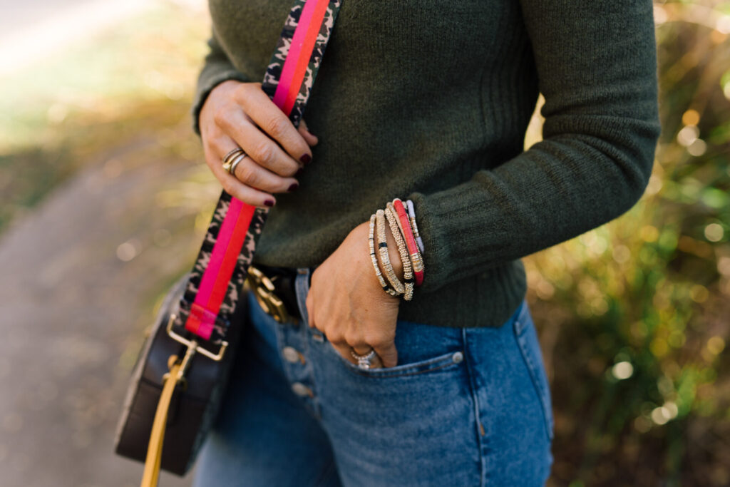 Year in Review by popular Nashville lifestyle blog, Hello Happiness: image of Natasha Stoneking wearing a Social Thread strap, green sweater, Gucci belt, button up jeans, and gold bracelets. 