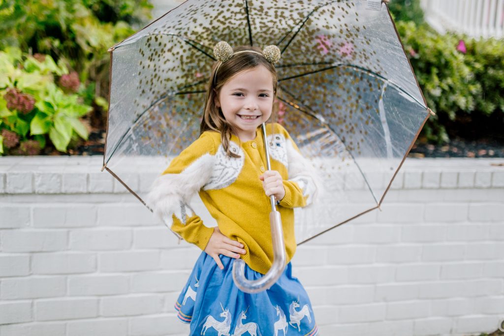 Party-Worthy Looks with the Boden Harry Potter Collection by popular Nashville fashion blog, Hello Happiness: image of a girl standing outside with an umbrella and wearing a Boden Hedwig Cardigan, Boden Appliqué Hem Skirt, Boden Grey Marl Ribbed Tights, and Boden Fun Low Tops.