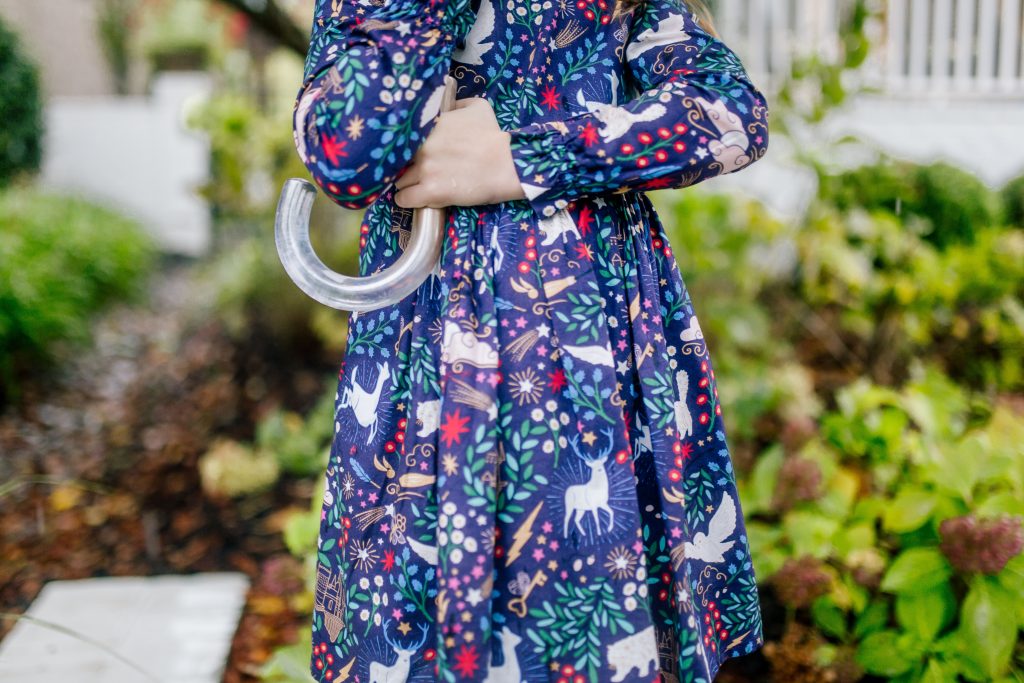 Party-Worthy Looks with the Boden Harry Potter Collection by popular Nashville fashion blog, Hello Happiness: image of a girl standing outside with an umbrella and wearing a Boden Forbidden Forest Dress, Boden pink sorbet Ribbed Tights, and Boden navy blue Leather Chelsea Boots.