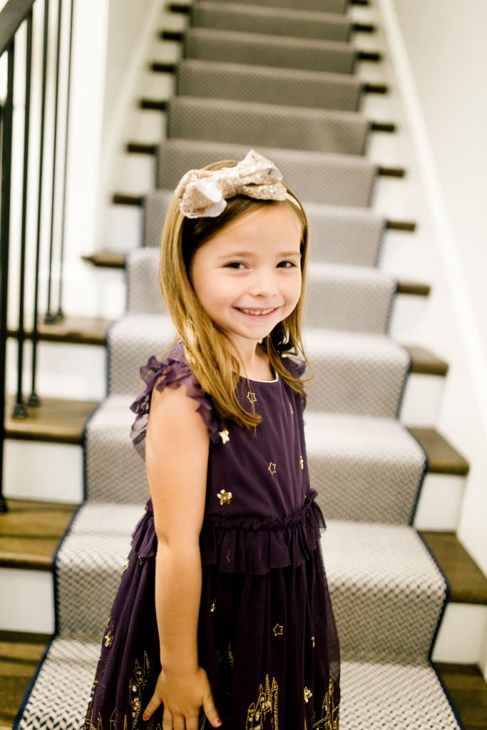 Party-Worthy Looks with the Boden Harry Potter Collection by popular Nashville fashion blog, Hello Happiness: image of a girl standing on some stairs and wearing a Boden Hogwarts Enchanted Tulle Dress, Boden High Tops, and Boden sparkly tights. 