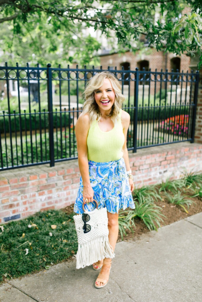 Walmart Scoop by popular Nashville fashion blog, Hello Happiness: image of a woman standing outside and wearing a Walmart Scoop Women’s Sweater Tank Top, Walmart Scoop Women's Short Wrap Skirt with Ruffle Hem, Walmart Scoop Macrame Wooden Handle Tote Bag, Walmart SODA Issue-s Casual Espadrilles Jute with Woods Open Toe Buckle Ankle Strap Wedge Sandal Shoes, and Walmart SA106 Thick Plastic Frame Round Horned Sunglasses for Women - Black.