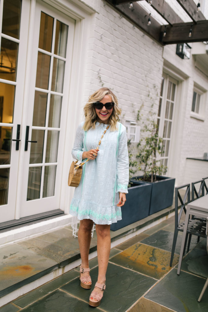 Sail to Sable by popular Nashville fashion blog, Hello Happiness: image of a woman wearing a Sail to Sable EMBROIDERED LONG SLEEVE DRESS WHITE OR SKY, Area Look Handmade Bamboo Round Crossbody Bag, Saks Fifth Avenue See by Chloé Krysty Floral Laser-Cut Suede Platform Sandals, and Nordstrom Quay Australia x JLO Limelight 54mm Oversize Sunglasses. 