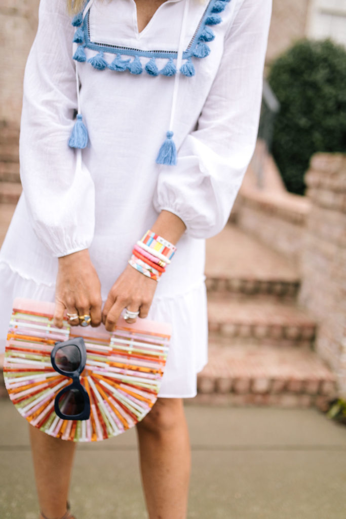 Sail to Sable by popular Nashville fashion blog, Hello Happiness: image of a woman wearing a Sail to Sable TASSEL FRONT FLOUNCE DRESS, See by Chloe Glyn Wedge Espadrilles, Candy Baublez custom stacks, Amazon Beauty YaYa Womens Bamboo/Acrylic Clutch Handbag Wooden Purse, Etsy Kristin Fast Limited Hoop Earrings, and Amazon zeroUV - Retro Oversized Square Sunglasses.