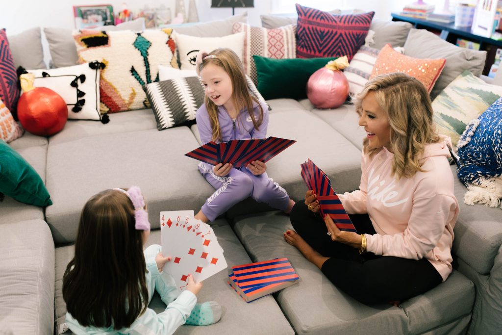 Everything Holiday with Academy Sports + Outdoors Gifts by popular life and style blog, Hello Happiness: image of a mom and her two daughters playing with a giant deck of Academy Sports + Outdoors giant playing cards.