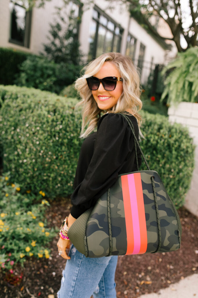 Social Threads by popular Nashville fashion blog, Hello Happiness: image of Natasha Stoneking standing outside and wearing a Amazon The Drop Women's Leona Short Puff Sleeve Crew Neck French Terry Sweatshirt, Social Threads Just Black Distressed Crop Kick Flare, Dillard's GB Here-4It Cheetah Print Haircalf Sneakers, and holding a Social Threads Hello Happiness Camo Striped Neoprene Tote.