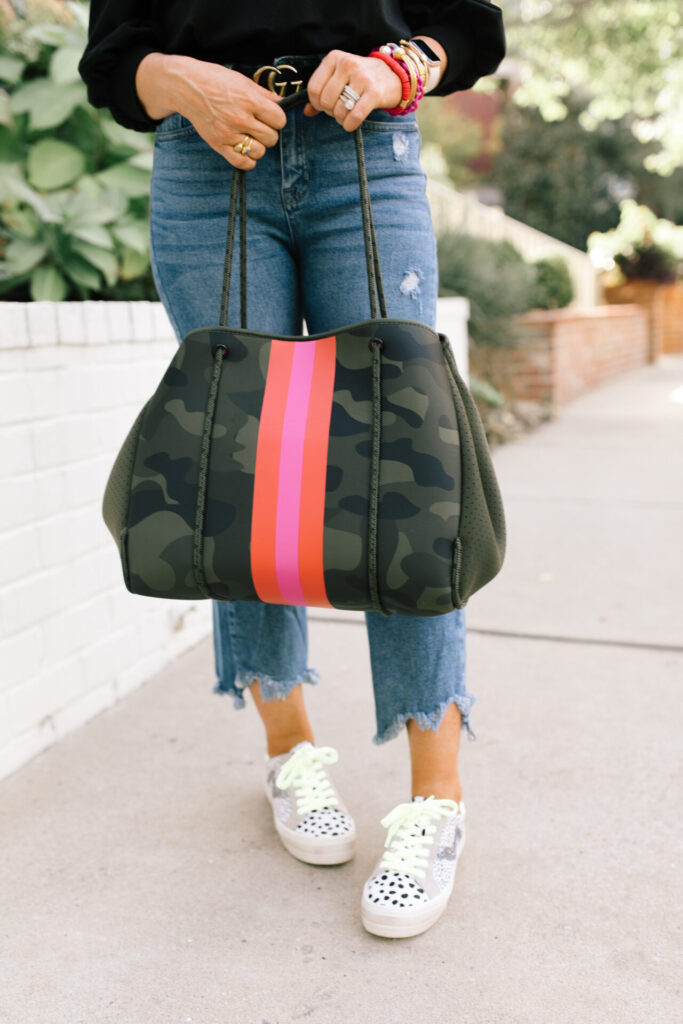 Social Threads by popular Nashville fashion blog, Hello Happiness: image of Natasha Stoneking standing outside and wearing a Amazon The Drop Women's Leona Short Puff Sleeve Crew Neck French Terry Sweatshirt, Social Threads Just Black Distressed Crop Kick Flare, Dillard's GB Here-4It Cheetah Print Haircalf Sneakers, and holding a Social Threads Hello Happiness Camo Striped Neoprene Tote.