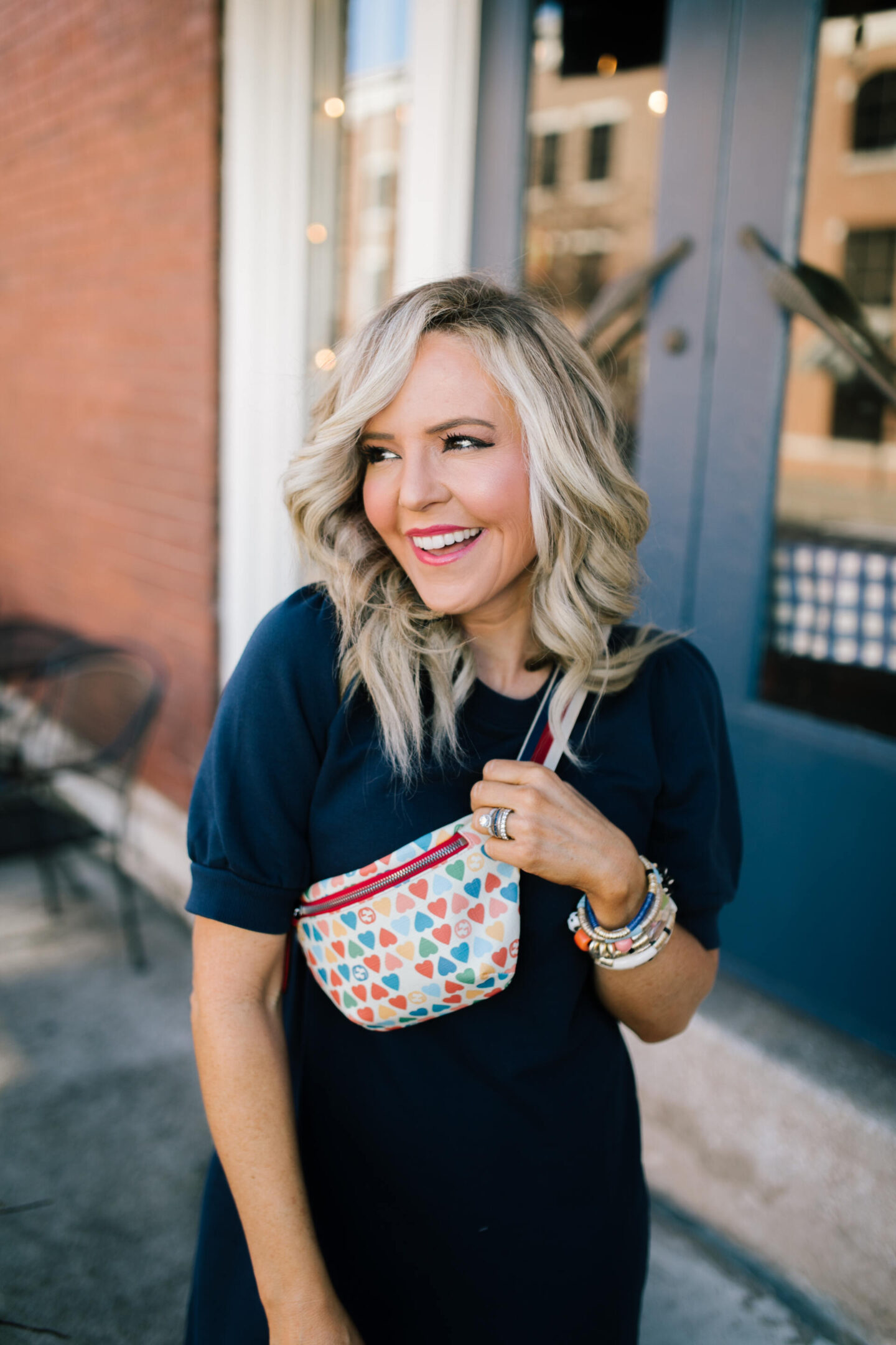 Belt Bag by popular Nashville fashion blog, Hello Happiness: image of Natasha Stoneking wearing a puff sweatershirt dress and heart crossbody bag. 