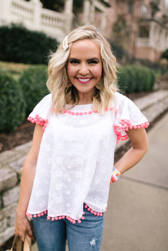 Sail to Sable by popular Nashville fashion blog, Hello Happiness: image of a woman wearing a Sail to Sable FLOUNCE SLEEVE POM POM TOP SKY, Social Threads Just Black Distressed Crop Kick Flare, Saks Fifth Avenue See by Chloé Krysty Floral Laser-Cut Suede Platform Sandals, Amazon pearl hair clip, and The Accessory Scout HAPPY DANCE EARRINGS.