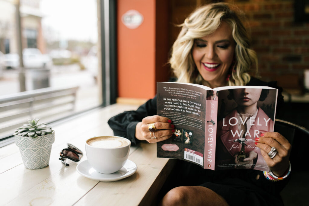 At Home Self Care by popular lifestyle blog, Hello Happiness: image of a woman wearing a black eyelet dress and reading The Lovely War.