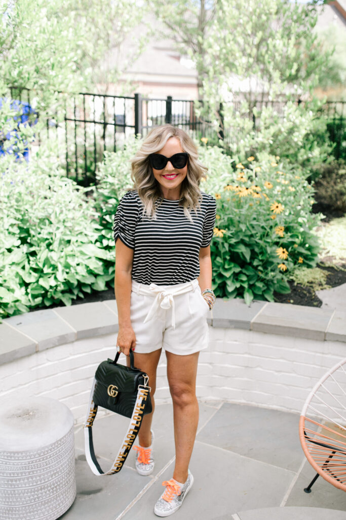 Gibson Look Road Trip by popular Nashville fashion blog, Hello Happiness: image of Natasha Stoneking wearing a Gibsonlook x DTKAustin Puff Sleeve Soft Tee, Freckles Mark Butterfly Sunglasses Semi Cat Eye Glasses, Ann Taylor The Marina Tie Waist Short, Gucci black GG Marmont small top handle bag, ZAGA SNEAKERS IN SILVER, and Social Threads Bag Strap.