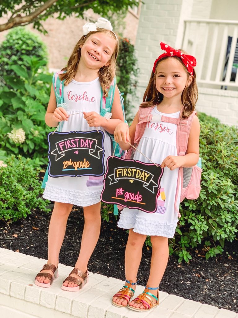 Caroline and Carson Go Back to School... And They're Off! by popular Nashville blog, Hello Happiness: image of two little girls wearing an Elegant Goods Shop dress and holding a Lovely Little Designs chalkboard sign. 
