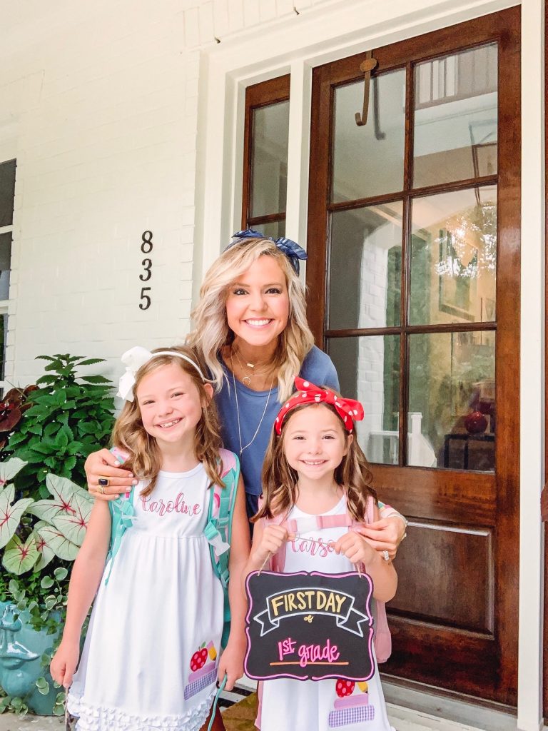 Caroline and Carson Go Back to School... And They're Off! by popular Nashville blog, Hello Happiness: image of two little girls standing outside with their mom and wearing an Elegant Goods Shop dress and holding a Lovely Little Designs chalkboard sign. 