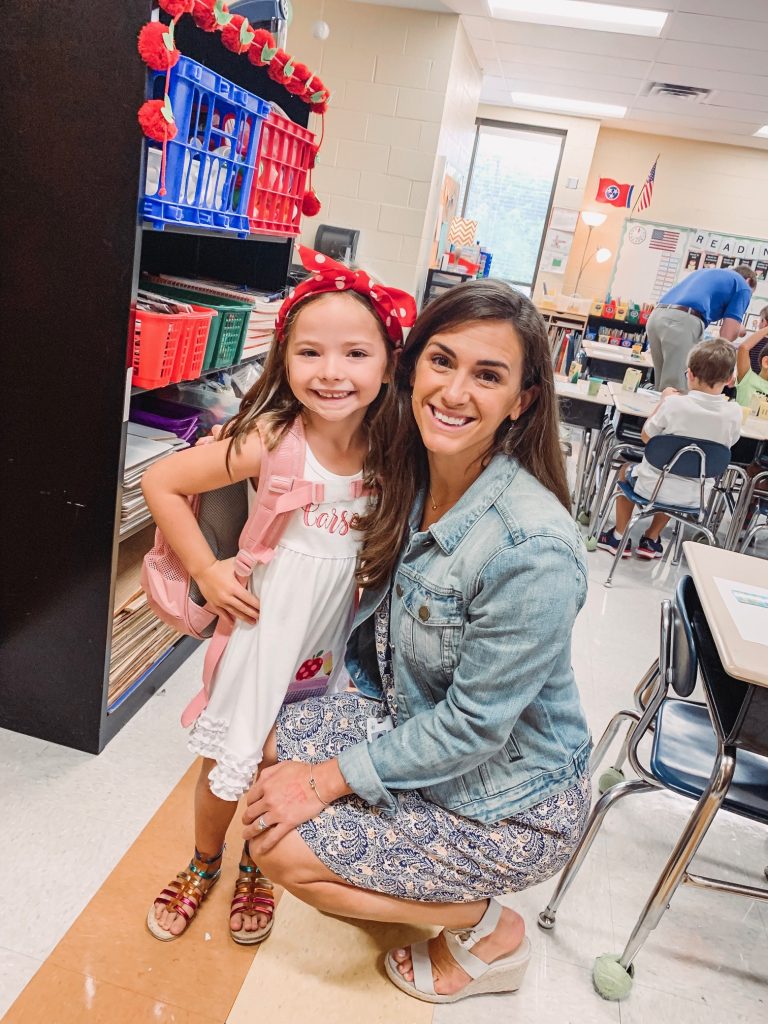 Caroline and Carson Go Back to School... And They're Off! by popular Nashville blog, Hello Happiness: image of a little girl standing inside with their teacher and wearing an Elegant Goods Shop dress.