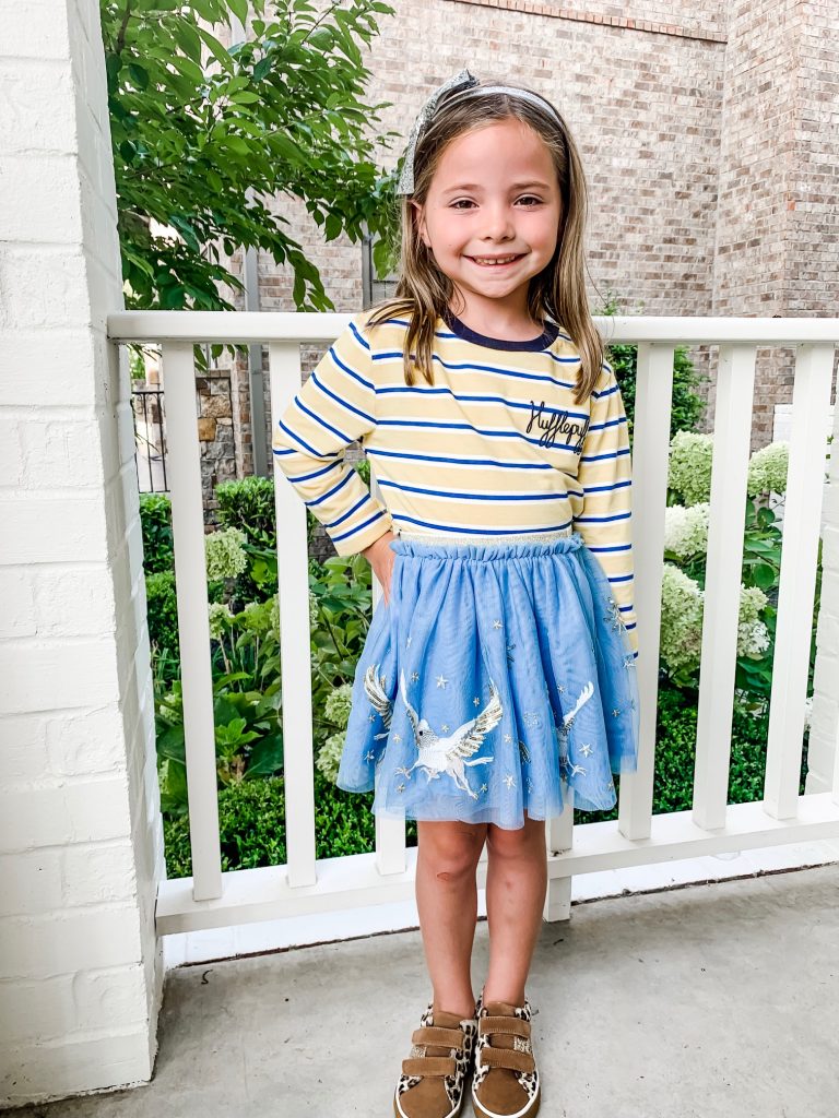 The Magical World of the Mini Boden Harry Potter Collection by popular Nashville fashion blog, Hello Happiness: image of two girls standing on a staircase and wearing Mini Boden House Breton - Gryffindor Red/Gold long sleeve shirt, Mini Boden Hippogriff Tulle Skirt, Mini Boden Hippogriff Bomber Jacket, and Fun Low Tops.