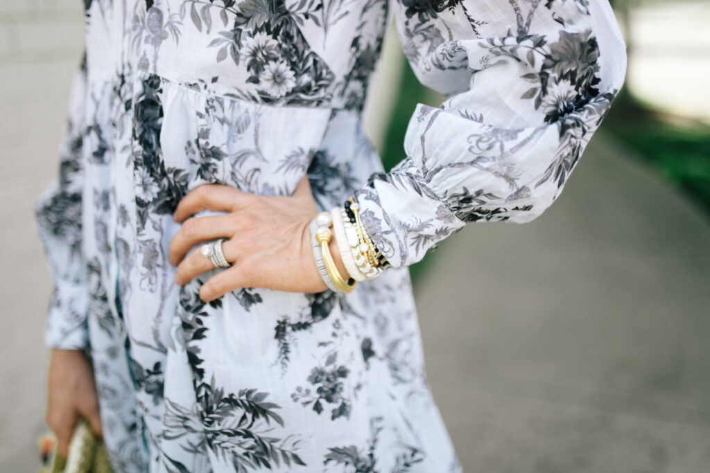 Anthropologie Sale by popular Nashville fashion blog, Hello Happiness: image of a woman standing outside and wearing a Anthropologie Lavinia Embroidered Shirtdress, See by Chloe Glyn Wedge Espadrilles, Hearne Dry Goods Co.Flower Dangle White, and holding a VINCE CAMUTO EMEI SMALL TOTE. 