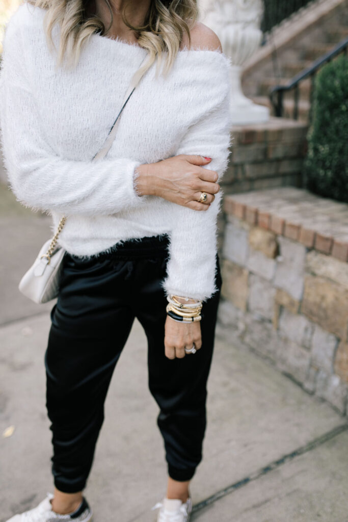 Holiday Collection by popular Nashville fashion blog, Hello Happiness: image of Natasha Stoneking wearing a feather knit off the shoulder sweater with velvet joggers and black earrings.  
