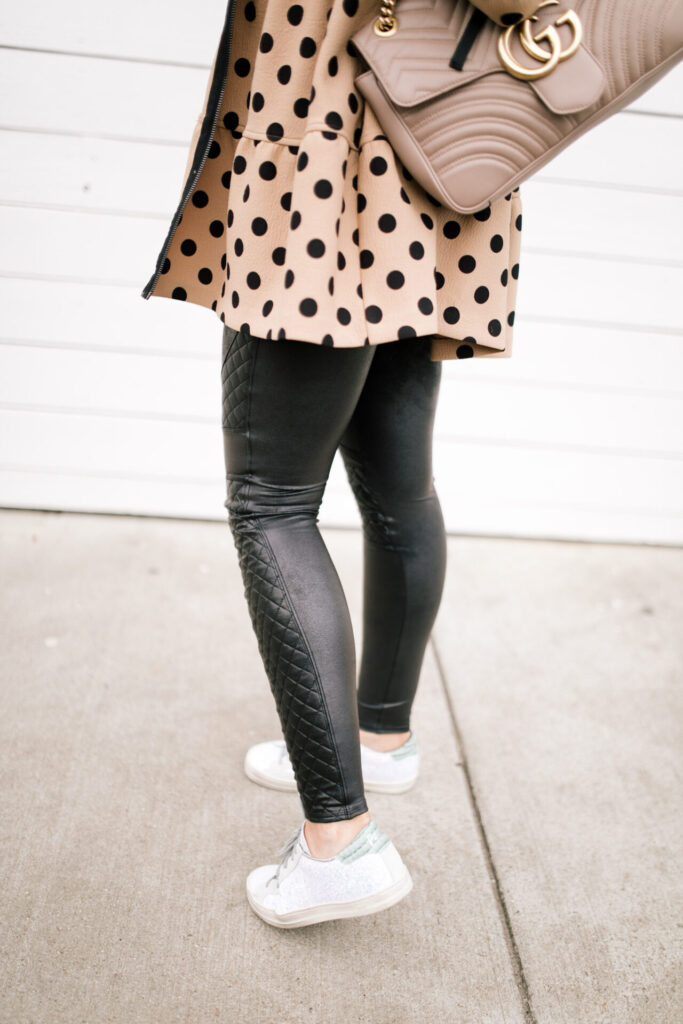 Cute Spring Shoes by popular Nashville fashion blog, Hello Happiness: image of  a woman wearing a pair of Evereve P448 Glitter Sneakers, Anthropologie Maybell Maybelle Tiered Coat, Buckle Z Supply The Star Print V-Neck T-Shirt, Etsy Kristin Fast Limited Animal Print Necklace- Leather Strap Necklace, and Spanx quilted faux leather quilted leggings. 