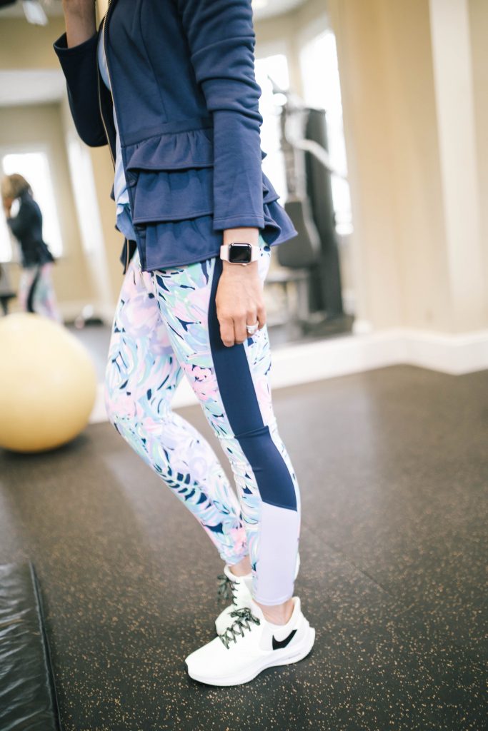 FWTFL... 2020 Style + My 1 Year Anniversary by popular Nashville life and style blog, Hello Happiness: image of a woman standing in a gym and wearing a Lilly Pulitzer AZELA RUFFLE FLEECE JACKET, Lilly Pulitzer LUXLETIC SUNRAY BRA TANK TOP, Lilly Pulitzer UPF 50+ LUXLETIC 26" WEEKENDER LEGGING, Athleta Hyper Focused Bra In Powervita, and women's Nike Womens Zoom Winflo 6.