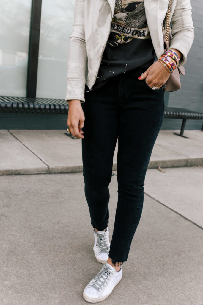 Evereve Nashville by popular Nashville fashion blog, Hello Happiness: image of a woman wearing a Evereve Marrakech Marci Moto Jacket, Evereve Chaser Born To Ride Tee, Evereve Agolde Toni Mid Rise Slim, Evereve P448 Glitter Sneaker, and enamel and beaded stack bracelets. 