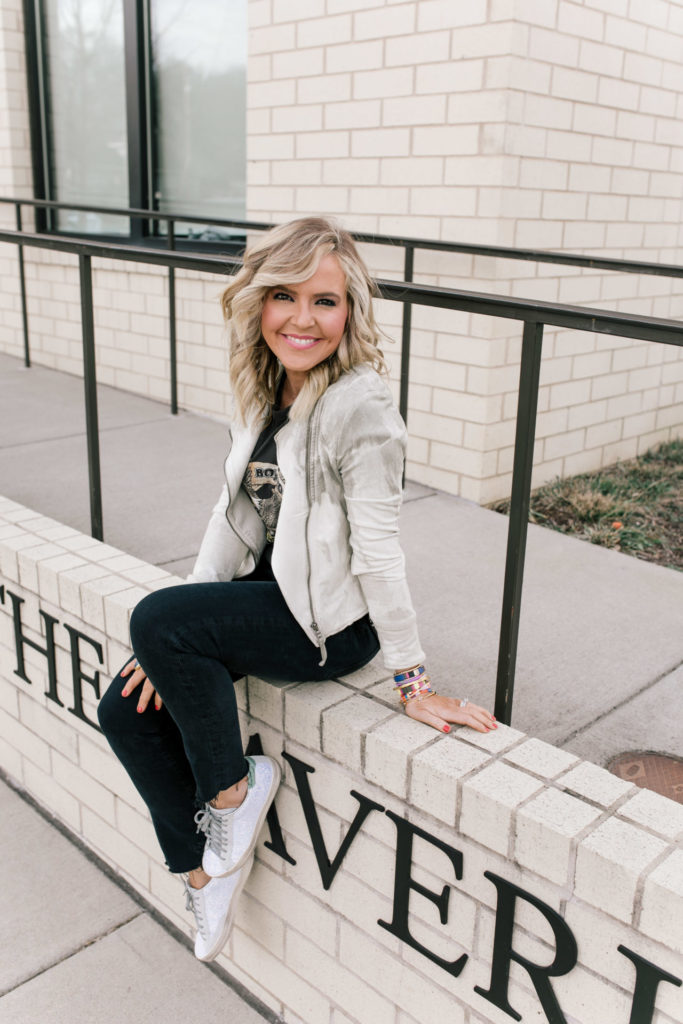 Evereve Nashville by popular Nashville fashion blog, Hello Happiness: image of a woman wearing a Evereve Marrakech Marci Moto Jacket, Evereve Chaser Born To Ride Tee, Evereve Agolde Toni Mid Rise Slim, Evereve P448 Glitter Sneaker, and enamel and beaded stack bracelets. 