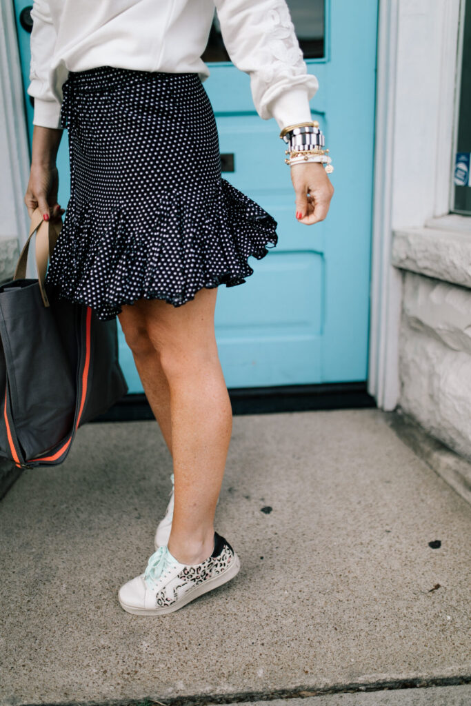 Cute Spring Shoes by popular Nashville fashion blog, Hello Happiness: image of a a woman wearing a Vici SWEET AS EVER COTTON + LACE SWEATSHIRT, Vici CATCH MY FLOW POLKA DOT RUFFLE MINI SKIRT, Nordstrom It's My Way 56mm Cat Eye Sunglasses QUAY AUSTRALIA, and Dolce Vita sneakers.
