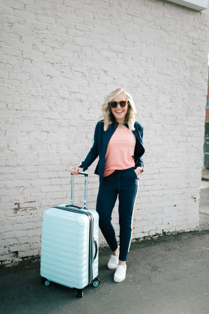 Cute Travel Outfit by popular Nashville fashion blog, Hello Happiness: image of a woman standing next to her Walmart iFly luggage wearing a Walmart Athletic Works Women's Performance Active Ombre Stripe Tank Top, Walmart Athletic Works Women's Athleisure Retro Stripe Track Jacket, Walmart Time and Tru Platform Twin Gore Slip On Sneaker, and Walmart Athletic Works Women's Athleisure Track Jogger Pants.