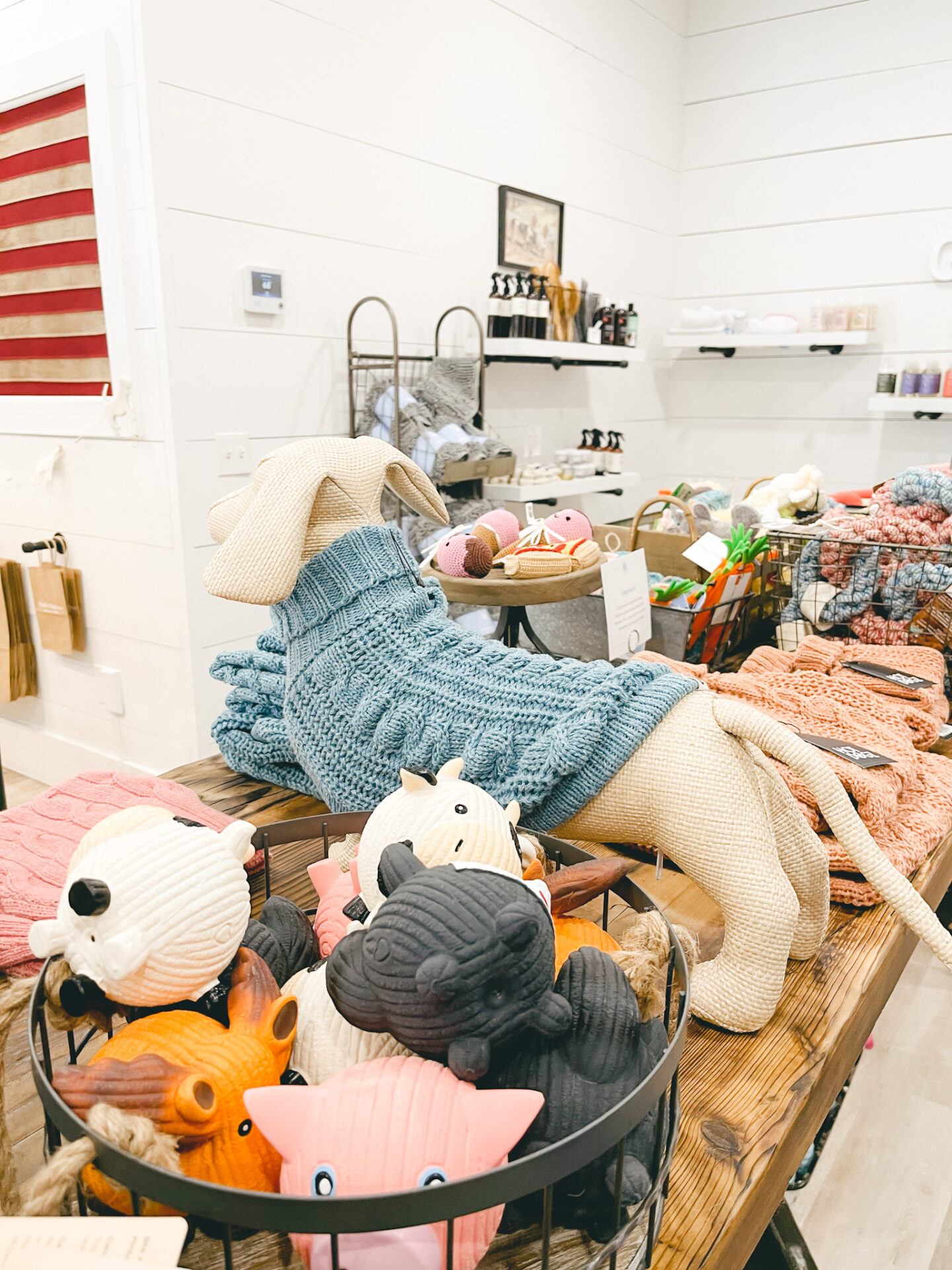 Dog Shops by popular Nashville lifestyle blog, Hello Happiness: image of dog toys in a metal wire basket and dog sweaters. 