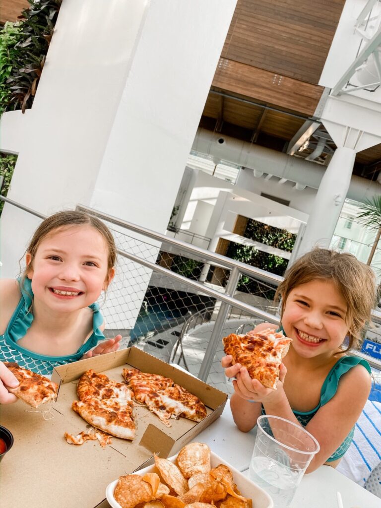 Gaylord Soundwaves by popular Nashville lifestyle blog, Hello Happiness: image of two girls wearing Target mermaid bikinis and eating pizza. 