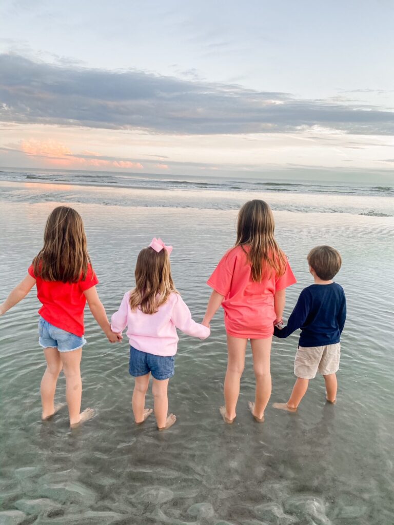 Year in Review by popular Nashville lifestyle blog, Hello Happiness: image of 4 young kids standing together and holding hands at the beach. 