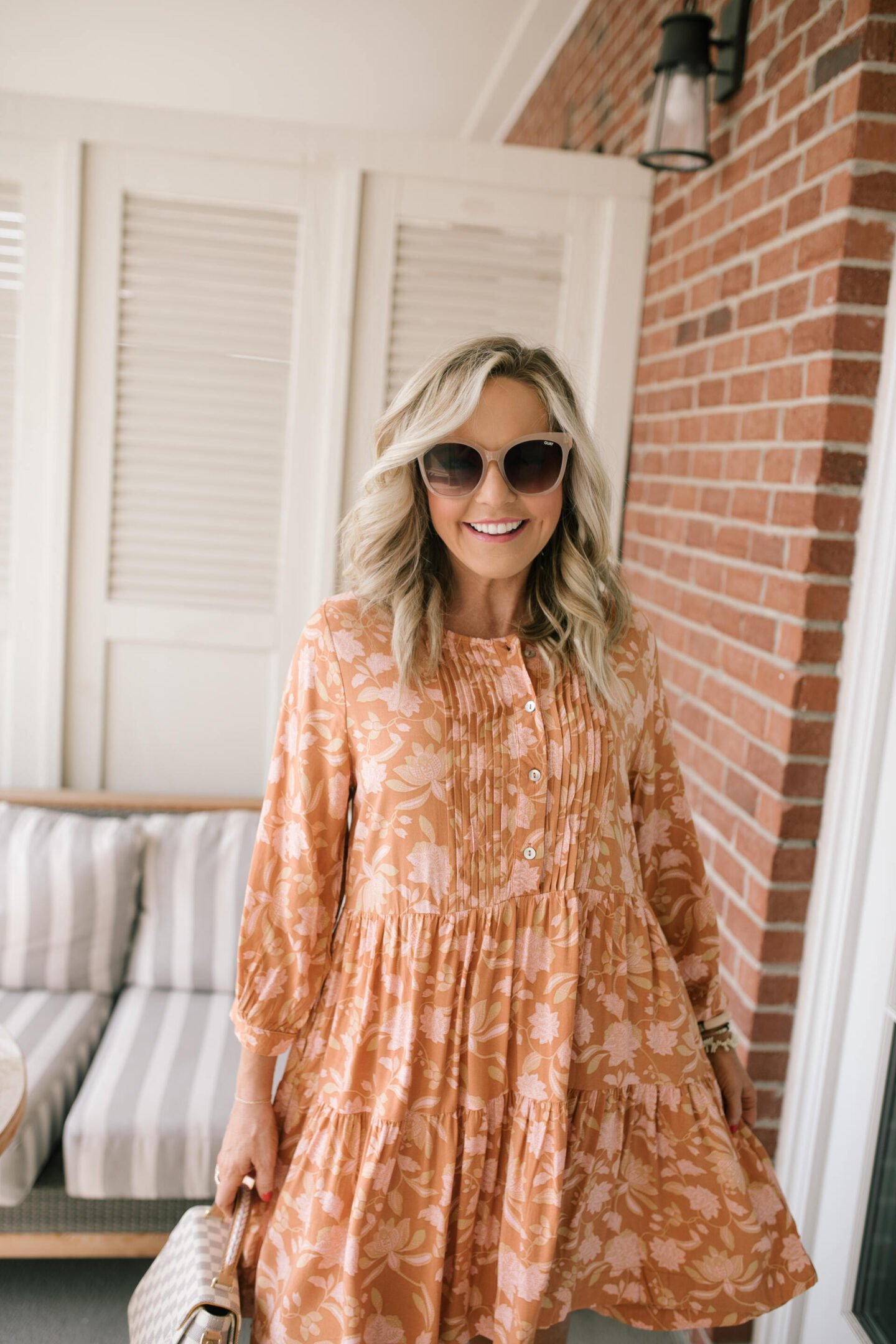 Orange Fashion by popular Nashville fashion blog, Hello Happiness: image of a woman wearing an orange floral print midi dress, sunglasses, and tan strap platform espadrille sandals. 