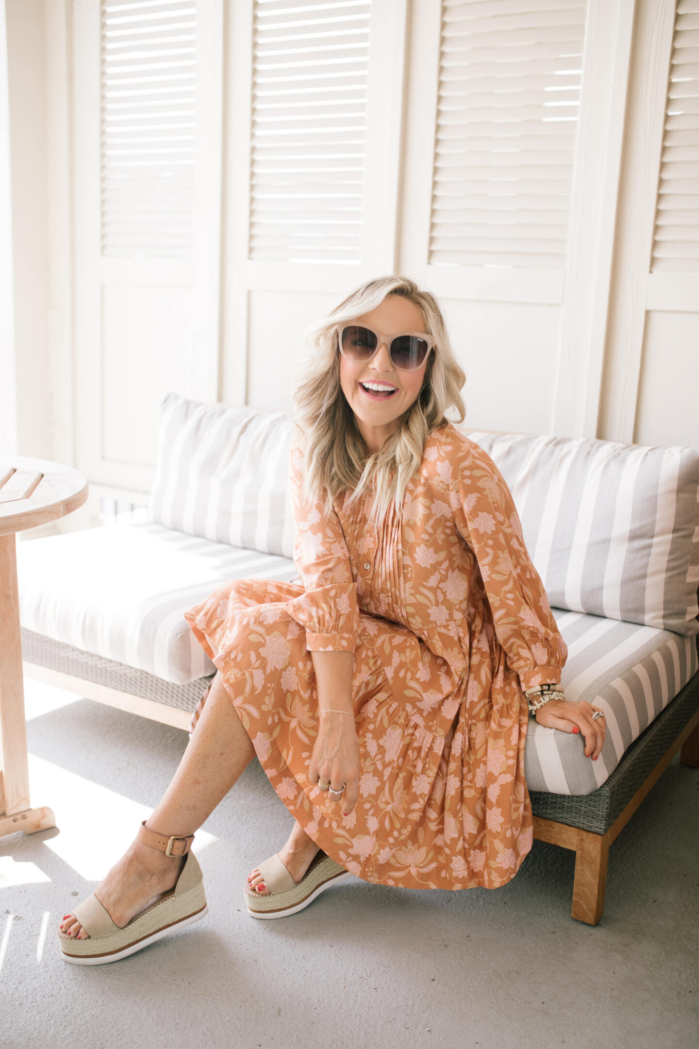 Orange Fashion by popular Nashville fashion blog, Hello Happiness: image of a woman wearing an orange floral print midi dress, sunglasses, and tan strap platform espadrille sandals. 