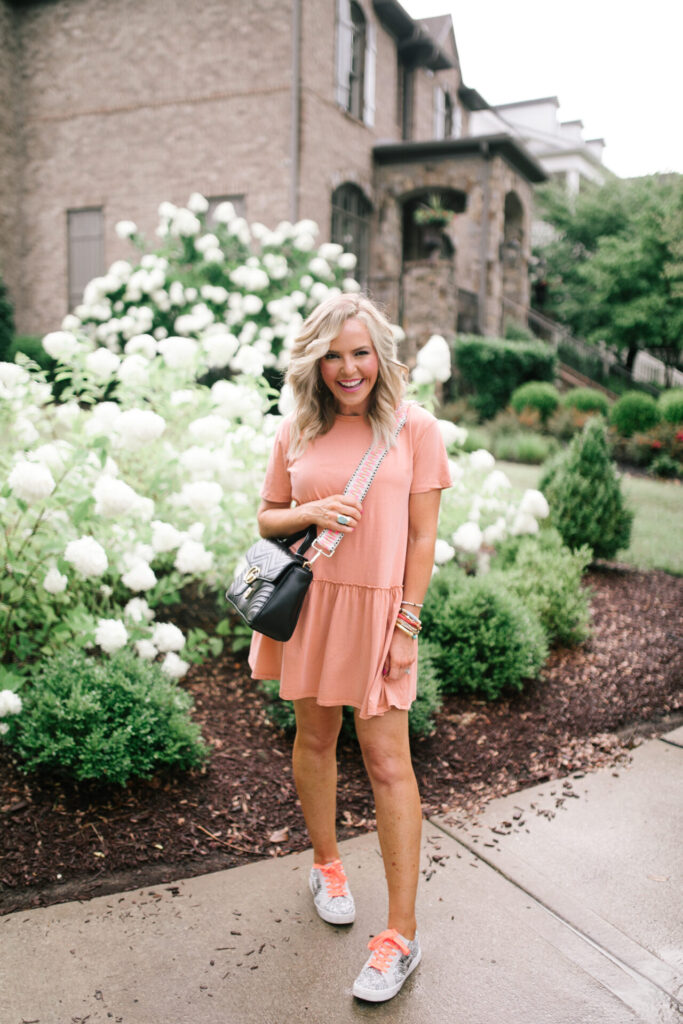 Football Game Outfits by popular Nashville fashion blog, Hello Happiness: image of Natasha Stoneking standing outside and wearing a ASOS Pull&Bear smock dress in washed coral and sneakers and carrying a Gucci Marmot purse with a Social Threads strap. 