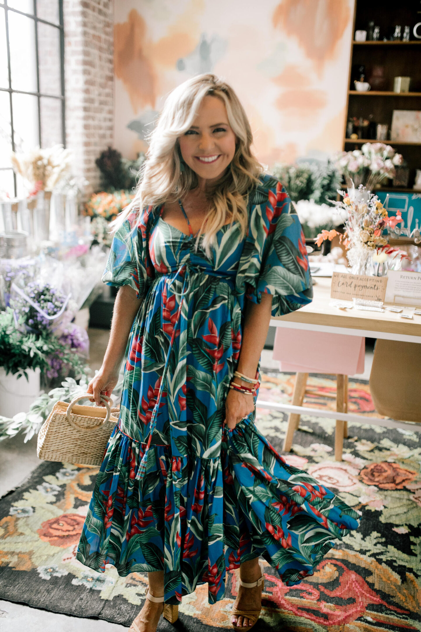 Birthday Wishlist by popular Nashville life and style blog, Hello Happiness: image of a woman wearing a Dream Garden midi dress and holding a woven hand bag. 