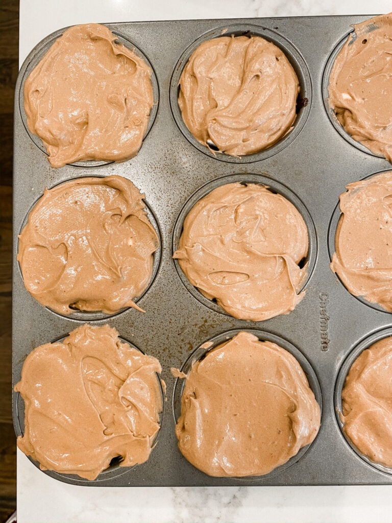 Frozen S'mores Cups by popular Nashville lifestyle blog, Hello Happiness: image of the graham cracker crusts topped with chocolate, mini marshmallows, and chocolate pudding in muffin tins. 