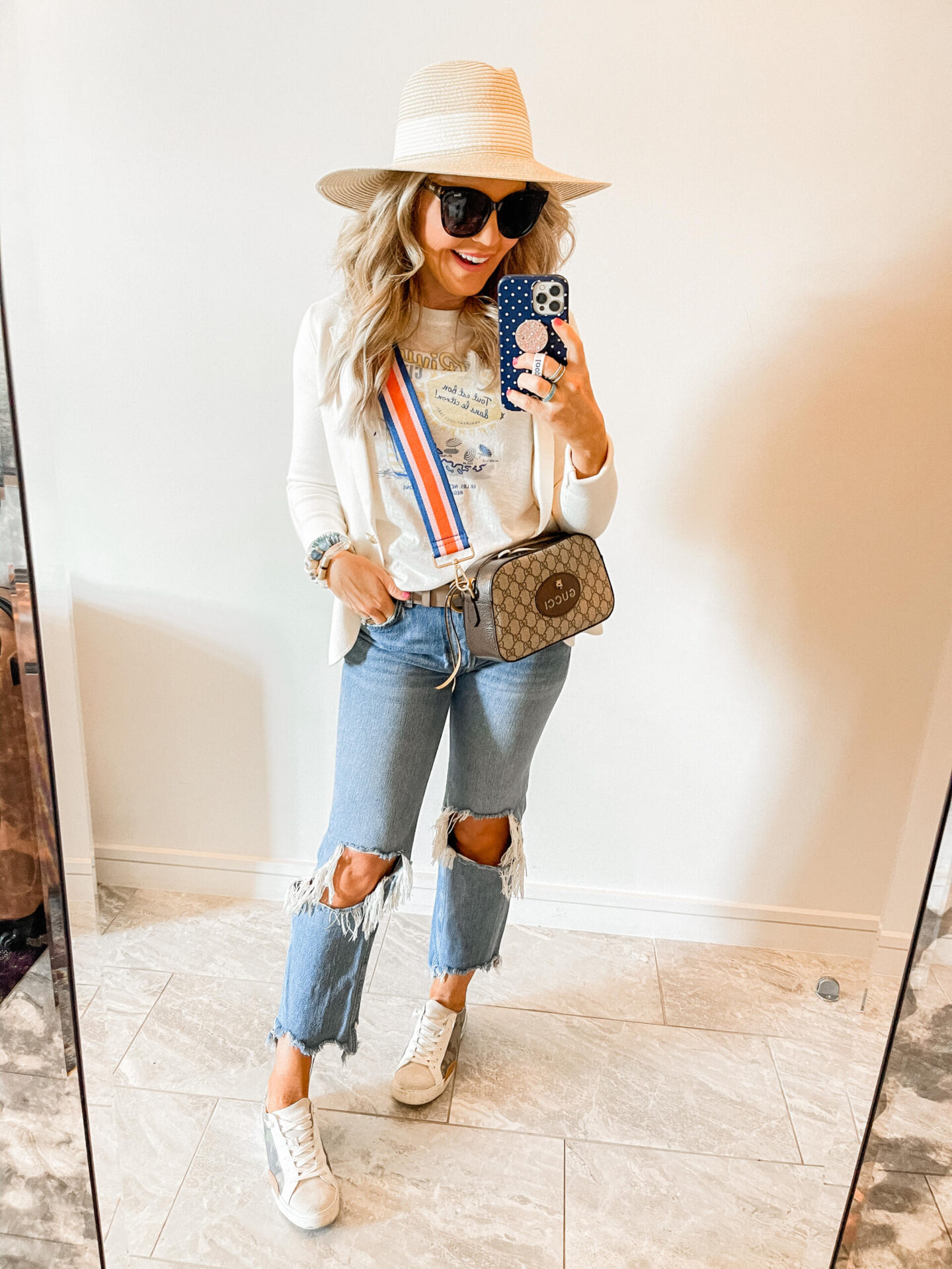 Girls Getaway by popular Nashville travel blog, Hello Happiness: image of Natasha Stoneking wearing a straw sun hat, deconstructed denim, Golden Goose sneakers, white graphic t-shirt, white blazer, and Gucci purse. 