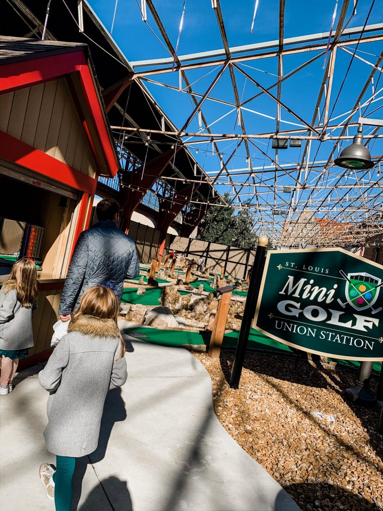 Meet Me for a Weekend in St. Louis | The Perfect Family Getaway by popular travel blog, Hello Happiness: image of a family doing mini golf at Union Station. 