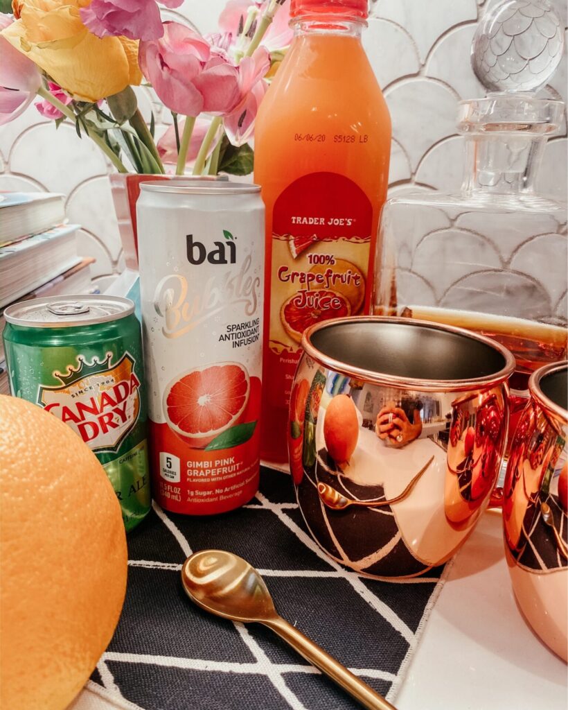 Summer Cocktail by popular Nashville lifestyle blog, Hello Happiness: image of a grapefruit whiskey slush in a Target Old Dutch Copper Hammered Moscow Mule Mugs, Bai Bubbles drink, Canada Dry Ginger Ale can, Trader Joe's Grapefruit Juice, whiskey decanter, gold spoon, and Minted Watch Hill  Cocktail Napkin Mixed Set.